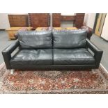 A contemporary black leather and chrome three seater settee,