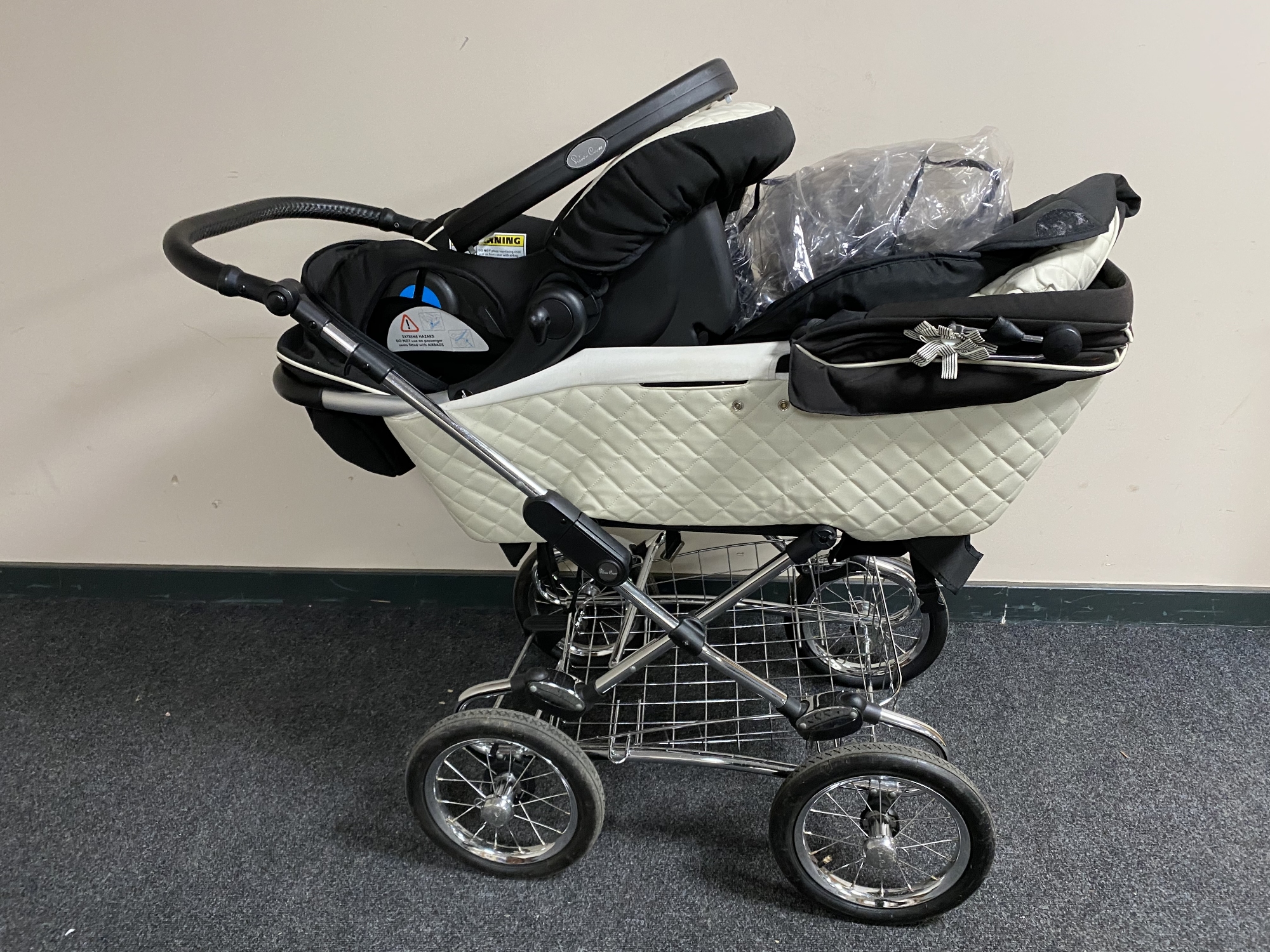 A Silver Cross push chair with rain cover and carry car seat