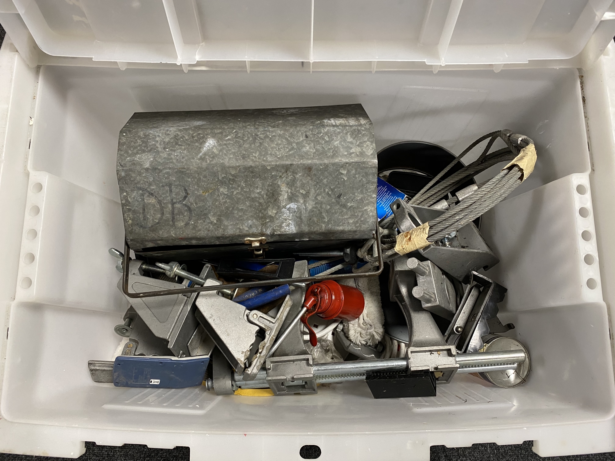 A plastic storage crate containing metal tool box and tools, oil can,