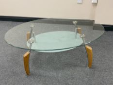 An oval glass topped coffee table on metal and wooden legs