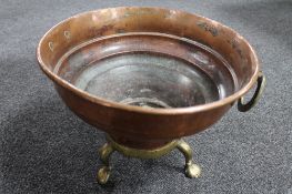 An antique copper bowl on raised brass paw feet