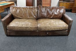 A large distressed brown leather three seater settee