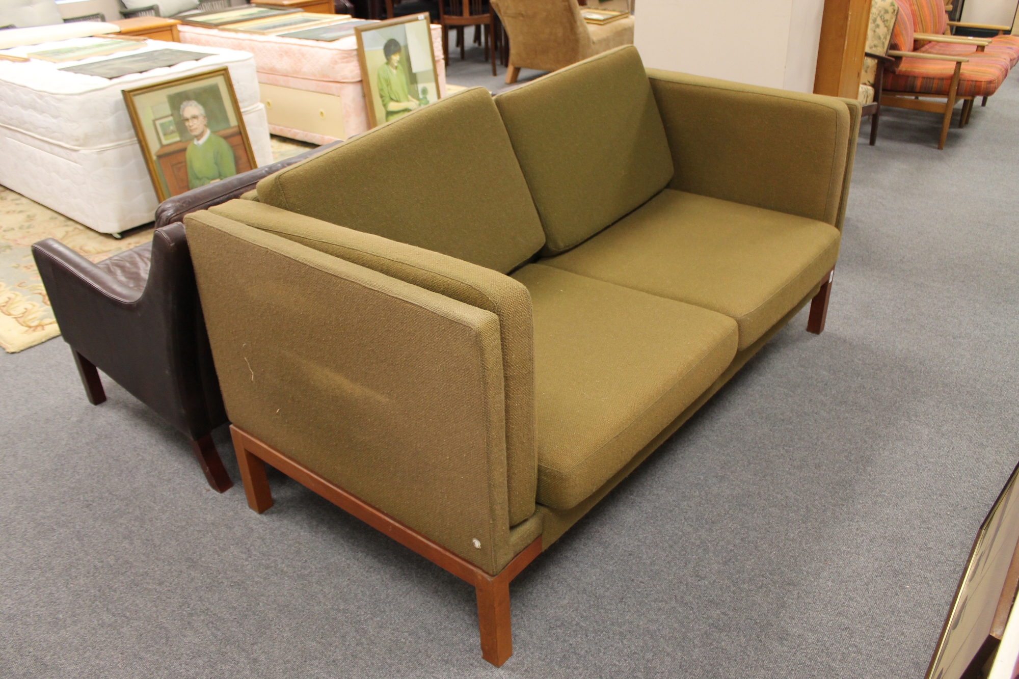 A mid 20th century Danish two seater settee in olive fabric on teak legs