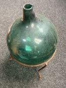 A green glass carboy on metal stand