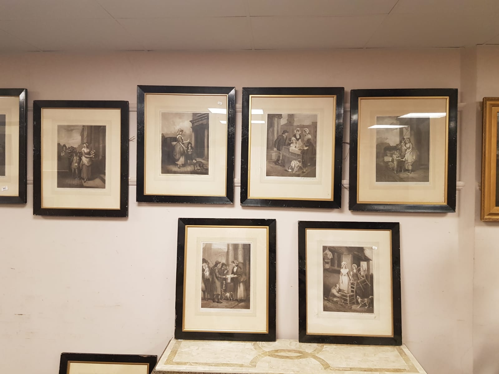 A set of 15 monochrome engravings depicting figures and taverns, in ebonised frames.