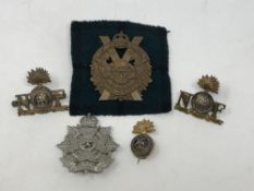 Five cap badges including Northumberland Fusiliers,