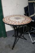 A circular pedestal tiled patio table