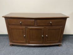 A stained pine bow fronted triple door sideboard