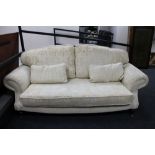 A contemporary two seater scroll arm settee in cream brocade.