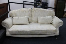 A contemporary two seater scroll arm settee in cream brocade.