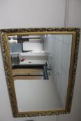 A gilt floral framed bevelled overmantel mirror