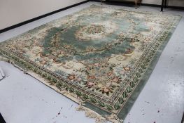 A Chinese floral embossed fringed carpet on green ground, approx. 300 cm 450 cm (excluding fringe).