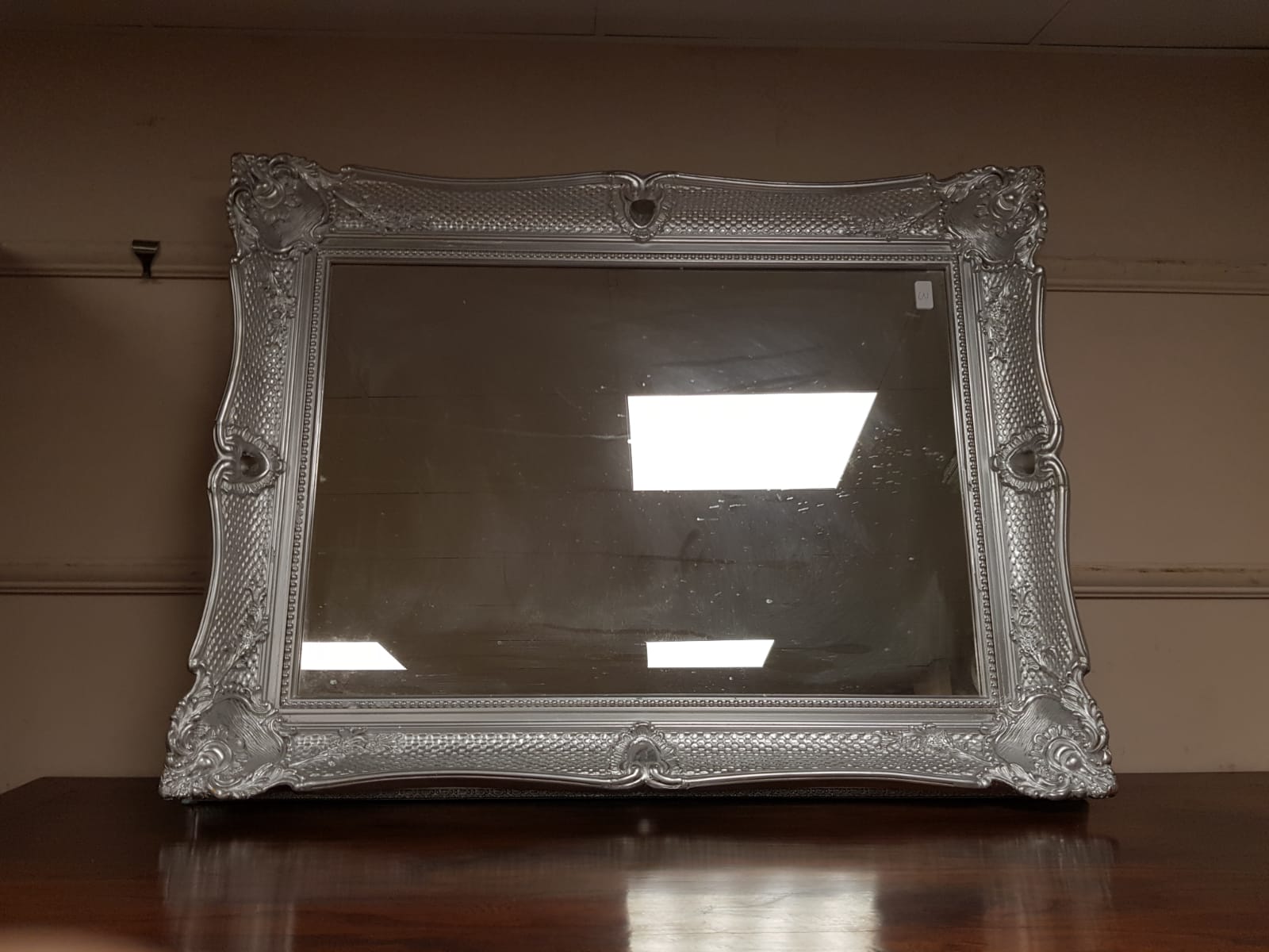 A chrome swept framed mirror,