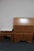 A 20th century teak bureau, nest of teak tables and an adjustable stool.