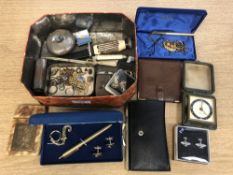 A tin of costume jewellery, travel clock, pens, knives,