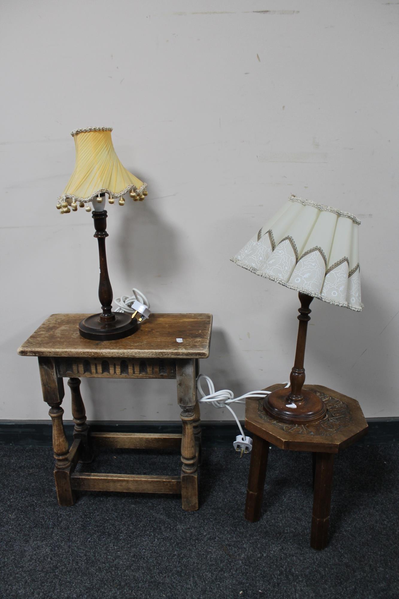 An antique oak stool, carved milking stool and two table lamps with shades.