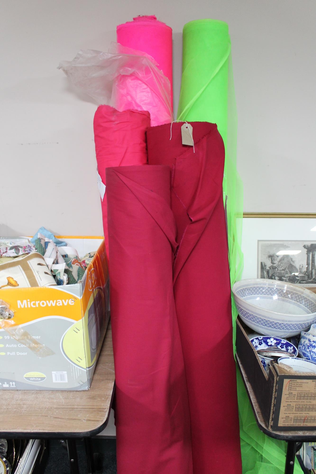 Three rolls of material (pink) together with two further rolls of netted fabric