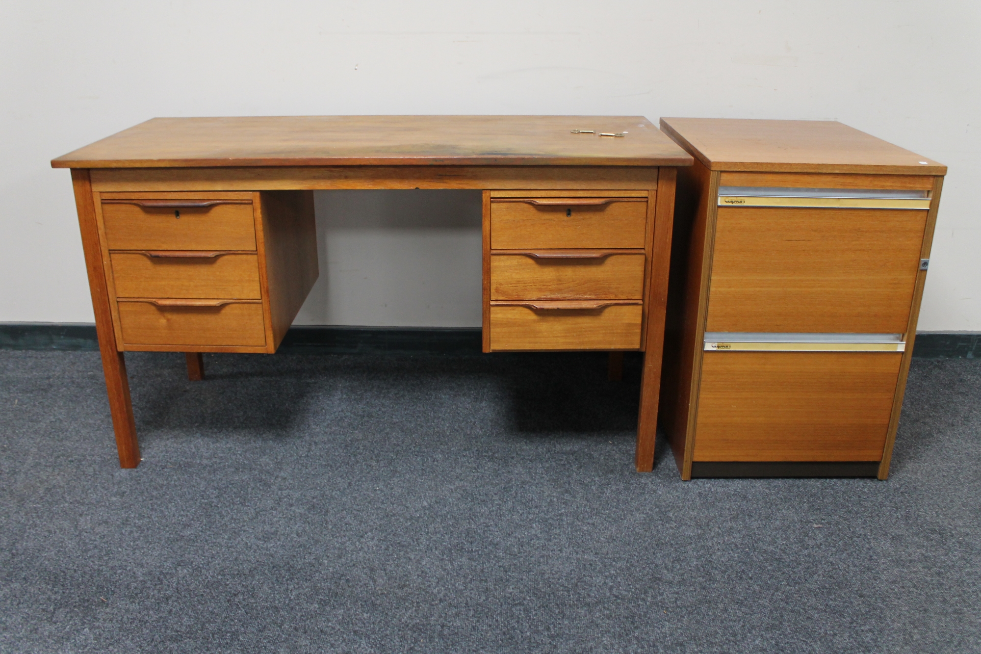 A mid 20th century teak twin pedestal writing desk and teak filing chest.