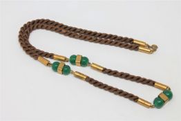 An Art Deco braided hair necklace with gilt metal mounts and studded green glass beads