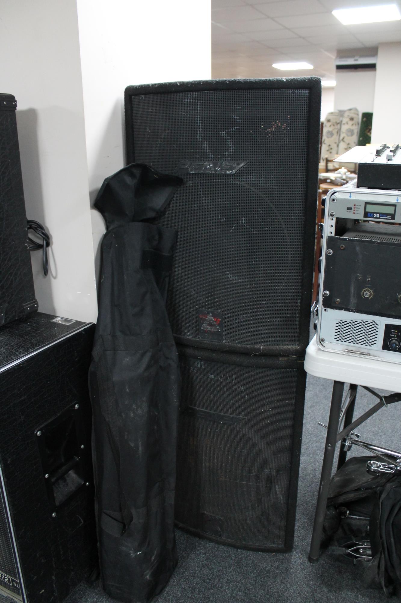 A pair of Peavey XT Series PA speakers and a bag of PA speaker stands.