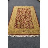 A fringed floral woolen rug on red ground.