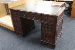 A mahogany twin pedestal writing desk fitted nine drawers and tooled leather inset panel.