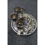 A circular plated tray containing a quantity of cutlery, goblets,