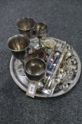 A circular plated tray containing a quantity of cutlery, goblets,