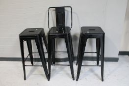 A pair of metal French style cafe stools together with a bar stool