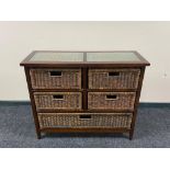 A contemporary glass topped chest fitted with five wicker drawers