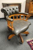 A reproduction yew wood green button leather chair,