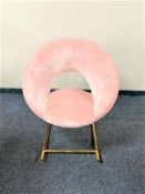 A contemporary rocking chair upholstered in pink fabric on metal legs