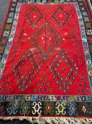 A fringed Eastern woolen rug of geometric design on red ground,