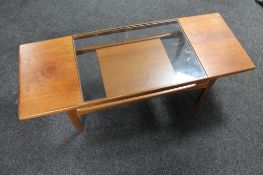A mid century teak coffee table with glass inset panel and undershelf
