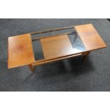 A mid century teak coffee table with glass inset panel and undershelf