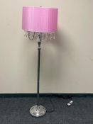 A contemporary metal four branch floor lamp with glass drops and pink shade