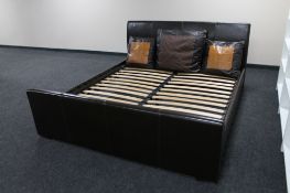 A 6' brown leather bed frame together with three large brown leather scatter cushions