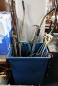 A plastic bin on wheels containing a assorted garden tools