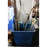 A plastic bin on wheels containing a assorted garden tools