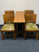 A 20th century teak drop leaf table together with a set of four panelled chairs