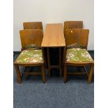 A 20th century teak drop leaf table together with a set of four panelled chairs