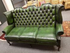 A green leather Chesterfield camel-backed settee,