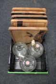 A crate of five wooden chopping boards together with three glass demijohns