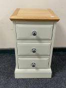 A contemporary oak topped three drawer bedside chest