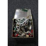 A tin of beaded necklaces, enamel badges,