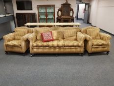 An Edwardian three piece lounge suite upholstered in golden striped fabric,