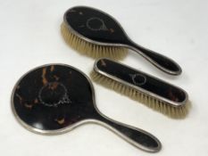 A three piece silver and tortoiseshell dressing table set