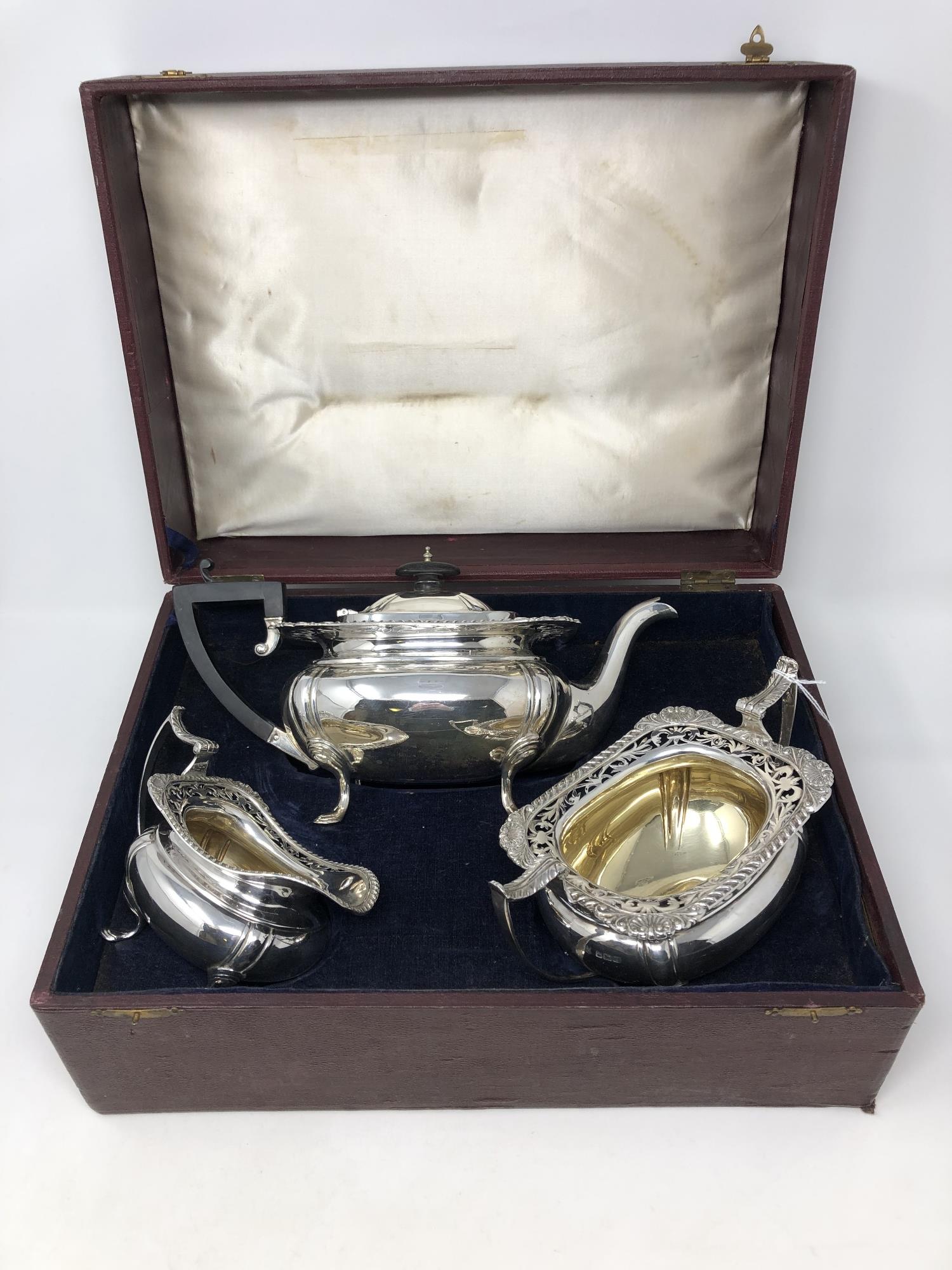 An ornate George V three piece boxed silver gilt tea set,
