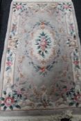 A fringed floral Chinese rug on beige ground