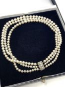 An antique triple strand pearl necklace with diamond set clasp
